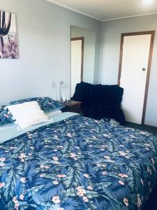 a bedroom with a bed with a blue blanket with flowers at Clyde Suite in Tauranga