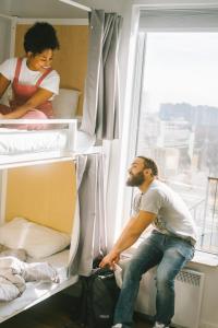 a man sitting on a bunk bed next to a window at Auberge Saintlo Montréal Hostel in Montréal