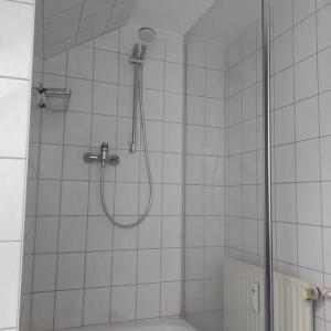 a shower in a white tiled bathroom at Pension Goldenes Vogtland in Adorf