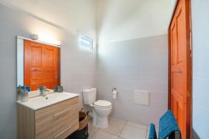 a white bathroom with a toilet and a sink at Séjour nature dans un écrin de modernité in Les Abymes
