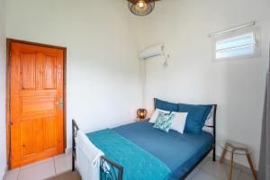 1 dormitorio con cama con sábanas azules y puerta naranja en Séjour nature dans un écrin de modernité en Les Abymes