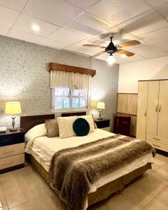 een slaapkamer met een groot bed en een plafondventilator bij Hotel Sans Souci in Belén de Escobar