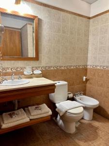 een badkamer met een toilet, een wastafel en een spiegel bij Hotel Sans Souci in Belén de Escobar