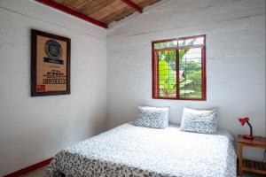Habitación blanca con cama y ventana en Hacienda Venecia Hostel en Manizales