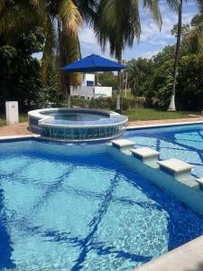 einen Pool mit einem Sonnenschirm und einem Brunnen in der Unterkunft Villa Elisa - Carmen de Apicalá in Carmen de Apicalá
