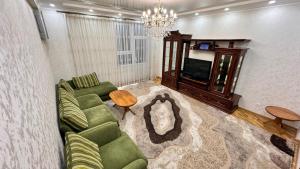 a living room with a green couch and a tv at Poytakht 80 Apartments in Dushanbe