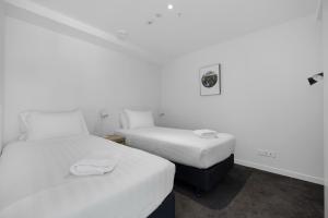 two beds in a small room with white walls at Residence du Parc - Luxury Apartment in Paraparaumu Beach