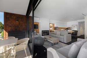 a living room with a couch and a table at Residence du Parc - Luxury Apartment in Paraparaumu Beach