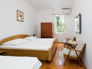 a bedroom with two beds and a chair at Apartments Dr. Vlasic in Podstrana