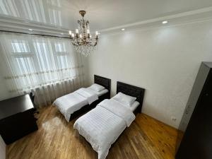 two beds in a room with a chandelier at Poytakht 80 Apartments in Dushanbe