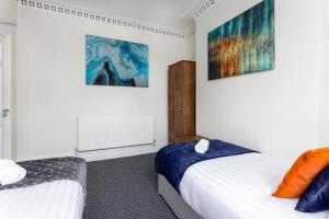 a bedroom with two beds and two paintings on the wall at Air Host & Stay - Newcombe House, 3 bedroom free parking in Liverpool
