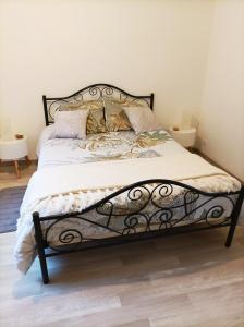 - un lit avec un cadre et des oreillers en métal noir dans l'établissement Gite Le Relais, à La Gacilly