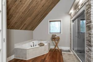 a bathroom with a white tub and a wooden ceiling at Le Fitchbay in Magog-Orford