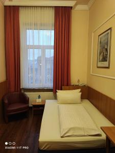 a bedroom with a bed and a window and a chair at Hotel Königshof in Mainz