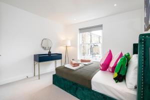 Belgravia Residence في لندن: غرفة نوم مع سرير مع وسائد وردية وأخضر