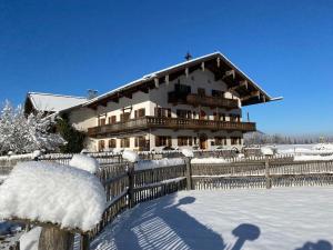 ein großes Haus mit einem Zaun im Schnee in der Unterkunft Knoglerhof in Ruhpolding