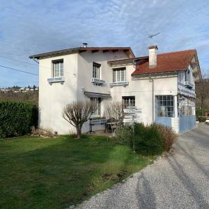 una casa blanca con un patio de hierba delante de ella en La Bigourdane, en Gerde