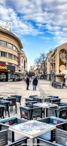 un groupe de tables et de chaises sur une rue de la ville dans l'établissement Guest rooms Super center PLOVDIV perfect location, à Plovdiv