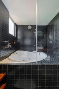 baño de azulejos negros con bañera y ventana en Stunning penthouse with terrace in Condesa, en Ciudad de México