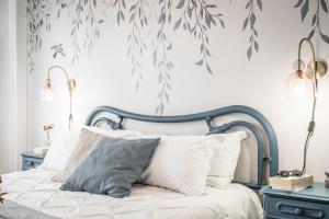 a bedroom with a bed with a blue frame and leaves wallpaper at CASA EMILIA - * In the HEART of MODENA * in Modena