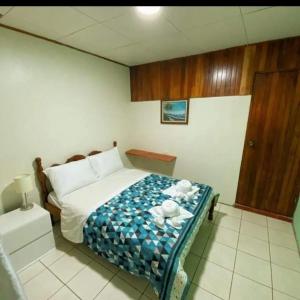 a bedroom with a bed with a blue and white blanket at Cabinas Morpho Gardens in Nuevo Arenal