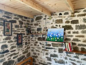 Habitación con una pared de piedra y una pintura de flores. en Stone House en Këlcyrë