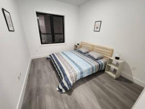 ein weißes Schlafzimmer mit einem Bett und einem Fenster in der Unterkunft Vast Fully Furnished 2-Bed Close to NYC in Bayonne