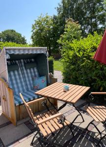einen Holztisch, eine Bank, einen Tisch und einen Picknicktisch in der Unterkunft Gulfhof Butendiek - Ferienapartments in Neuharlingersiel