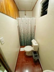 a small bathroom with a toilet and a shower at Cabinas Morpho Gardens in Nuevo Arenal