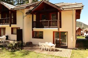 a house with a table and chairs on a deck at Chalet La Combe D Or - Superbe chalet 10 personnes MAE-3584 in Le Mélézet