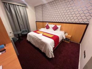 a hotel room with a large bed with red and white sheets at فندق رفاق Refaq Hotel in Makkah