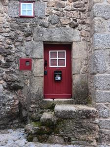 una puerta roja en el lateral de un edificio de piedra en Recanto da Pedra, en Linhares