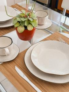 a glass table with plates and a potted plant on it at Morada Verde - AP 2 quartos in São José