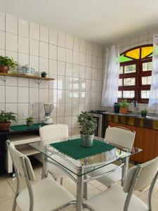 a kitchen with a glass table and white chairs at Morada Verde - AP 2 quartos in São José