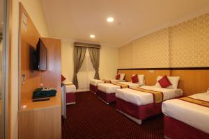 a hotel room with four beds and a television at فندق رفاق Refaq Hotel in Makkah