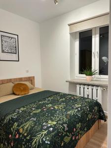 een slaapkamer met een bed met een groene deken en een raam bij Apartament Zasanie 2 Przemyśl in Przemyśl