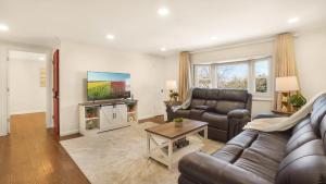 a living room with a couch and a tv at The Mod Pad! 15 min from Airport, Free Parking! in Valley Stream