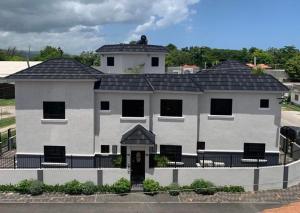 a large white house with a black roof at Meadows Place in Montego Bay