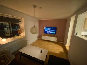 a living room with a tv and a white table at Norðragøta in Norðragøta