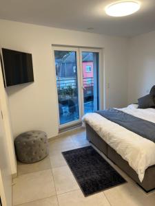 1 dormitorio con 1 cama, TV y ventana en Appartement de luxe avec parking, en Kayl