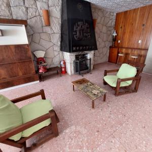 a living room with a stone fireplace and chairs at Hostel De Oto in Godoy Cruz
