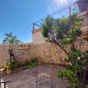 a stone wall next to a building with a tree at Hostel De Oto in Godoy Cruz
