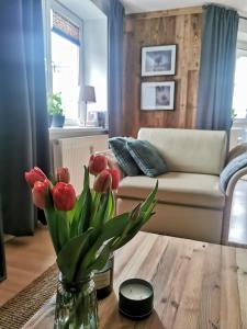 a living room with a vase of flowers on a table at Mozaika Art Apartment PL LT EN in Suwałki
