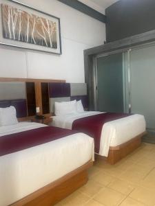 a hotel room with two beds and a window at Hotel Alhaja in Puebla