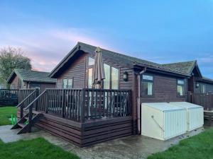 uma casa com um deque com um guarda-chuva em Cosy 3 Bed Lodge in Hoburne, Cotswolds em South Cerney