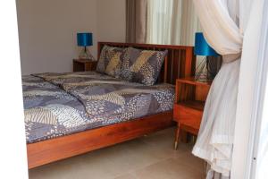 Shalom Villas في Mamobi: غرفة نوم مع سرير وطاولة مع مصباحين