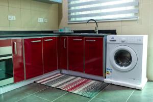 uma cozinha com armários vermelhos e uma máquina de lavar roupa em Shalom Villas em Mamobi