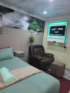 a bedroom with two beds and a chair and a flat screen tv at Tshedza Guest House in Pretoria