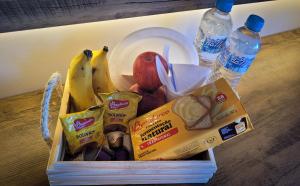 納維根特斯的住宿－Bela Vista - Hospedagem，一个带香蕉苹果和面包的盒子和两瓶水