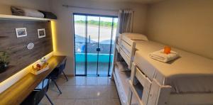 Schlafsaal mit einem Etagenbett, einem Schreibtisch und einem Balkon in der Unterkunft Bela Vista - Hospedagem in Navegantes